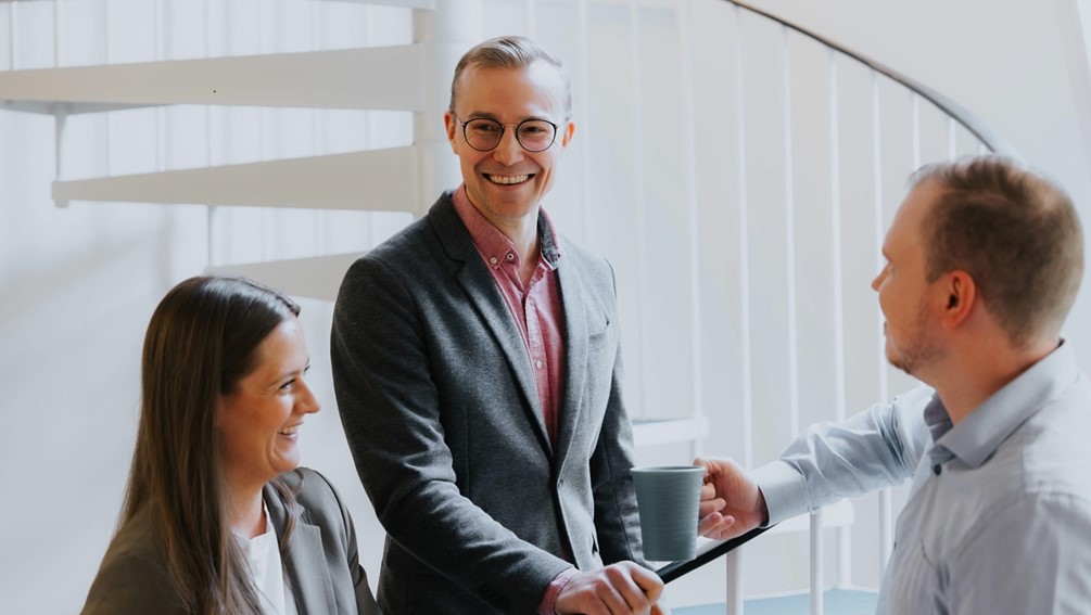 Company employees discussing over a cup of coffee - create a more engaged work community with employee surveys.