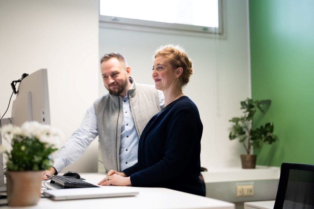 Two people comparing survey tool options from a computer screen.